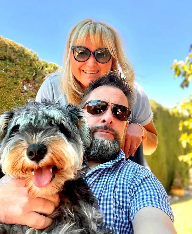 Ziggy le schnauzer, Mark et Karen, souriants au soleil dans leur jardin en Dordogne